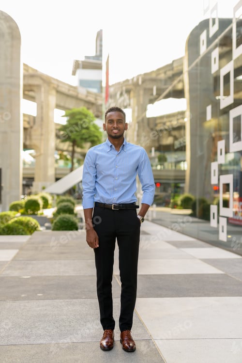 Preview: Full length shot of handsome black African businessman outdoors in city during summer