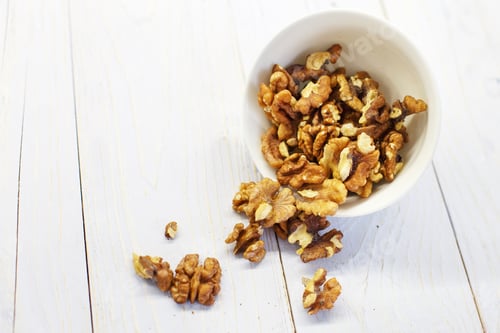 Preview: walnuts in the white bowl close. peeled walnuts on white colored old vintage wooden backdrop.