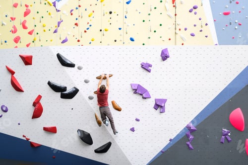 Preview: Muscular man practicing climbing on a climbing wall of a rock climbing wall