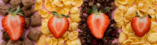 Preview: top view of fresh strawberries on assorted breakfast cereals and granola on pink, banner
