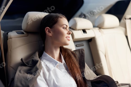 Preview: Woman sitting in back seat of car, head resting on armrest, gazing sideways