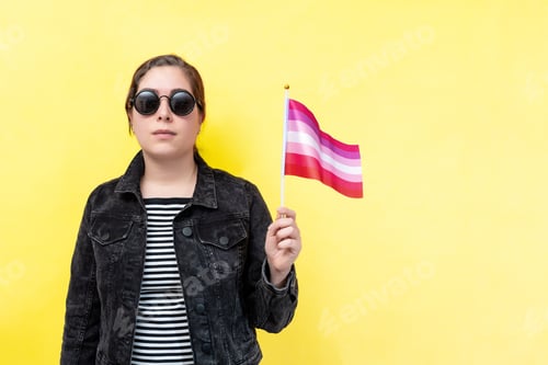 Preview: Serious young woman hold lesbian pride flag. Lgbtq+, queer concept.
