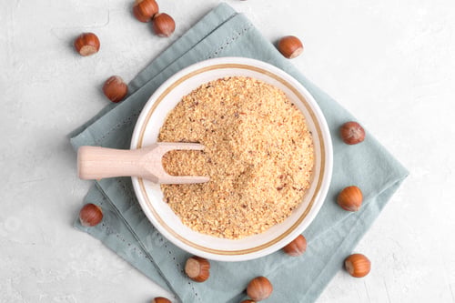Preview: Raw Ground Hazelnut Flour in a Bowl with whole nuts on grey table