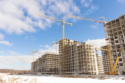 Construction Cranes and Buildings Against a Blue Sky