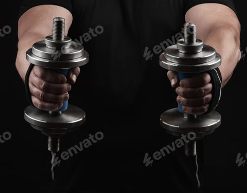 Preview: Adult man in black clothes holds steel dumbbells in his hands