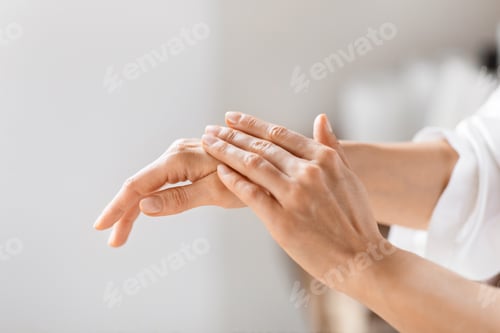 Preview: Woman in white robe applying hand cream