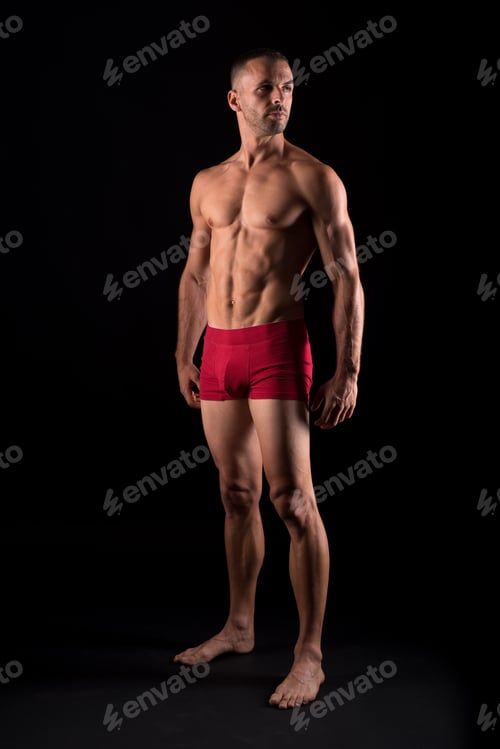 Preview: Studio photo of strong male in pants standing, black background