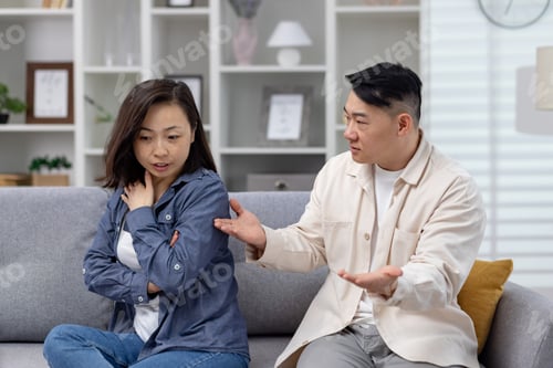 Preview: Asian couple having a serious discussion on the couch in their living room
