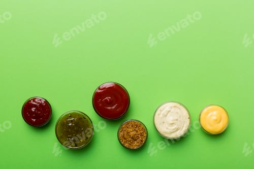 Preview: Different types of sauces in bowls on a colored Board . Top view. various sauces copy space