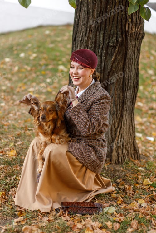 Preview: Brunette in vintage clothes and a hat with a dog in an autumn park. Retro style