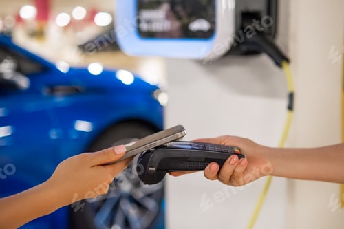 Preview: Person makes a contactless payment at a terminal near a charging station with a mobile device