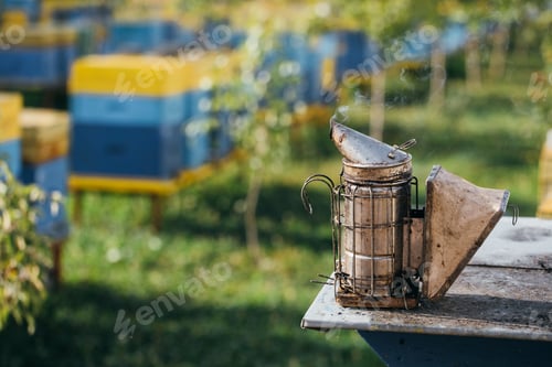 Preview: Beekeeper Smoker smokes white smoke. Apiary background. Beekeeping tool close up.