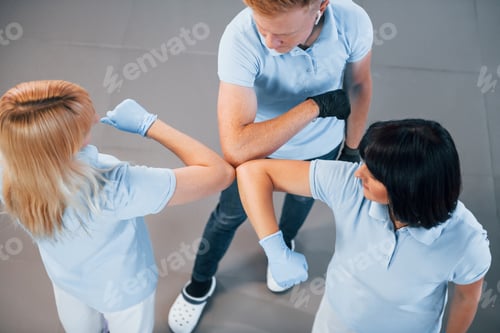 Preview: Touches by the elbows. Group of workers clean modern office together at daytime