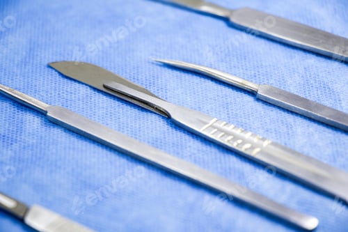 Preview: Closeup of a dissection kit with scalpels on a blue medica cloth
