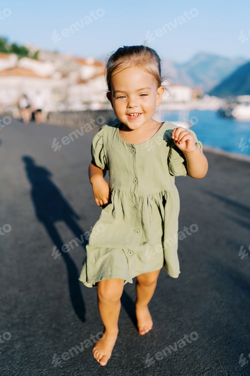 Preview: Little smiling girl runs barefoot along the embankment
