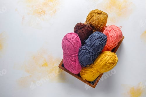 Preview: Balls of yarn in different colors with knitting needles.