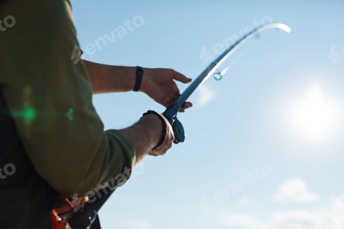 Preview: Man holding fishing tackle while fishing in the morning