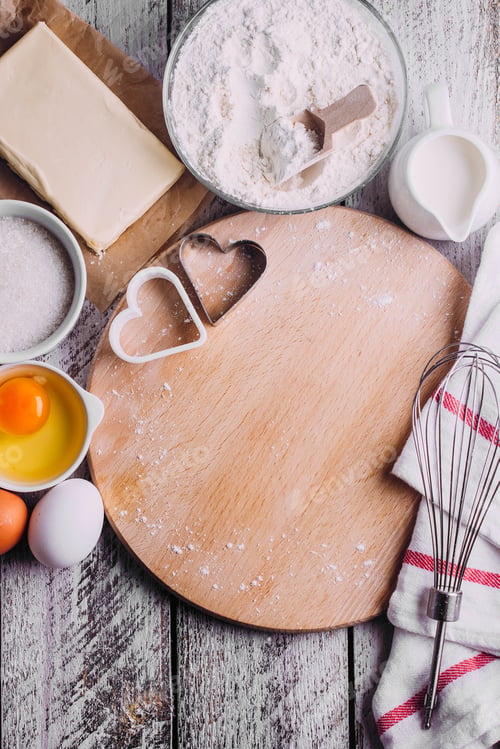 Preview: Ingredients for baking Valentines day cake - eggs, flour, milk, butter, sugar on wooden board.