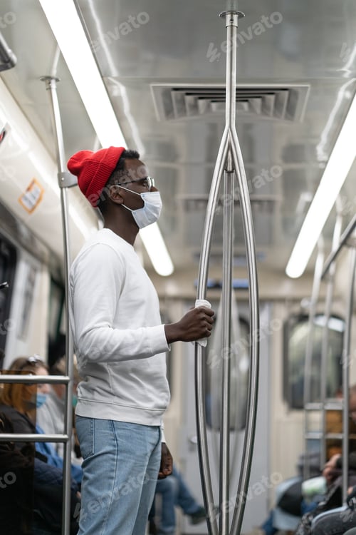 Vista previa: Black man wear face mask in subway train during covid19 pandemic holding handrail through the napkin