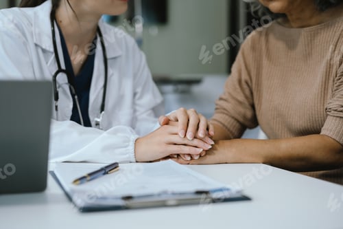 Preview: Friendly female doctor hands holding patient hand sitting at the desk for encouragement