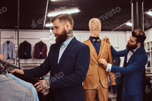 Preview: Two stylish shop assistants elegantly dressed working in a menswear store.