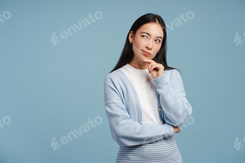Preview: Pensive, attractive, Asian woman looking away and touching her chin in contemplation looking away