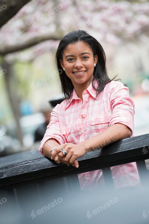 Preview: A young woman with black hair, looking over a railing and smiling.