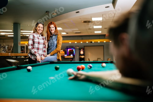 Preview: Happy friends enjoying playing pool