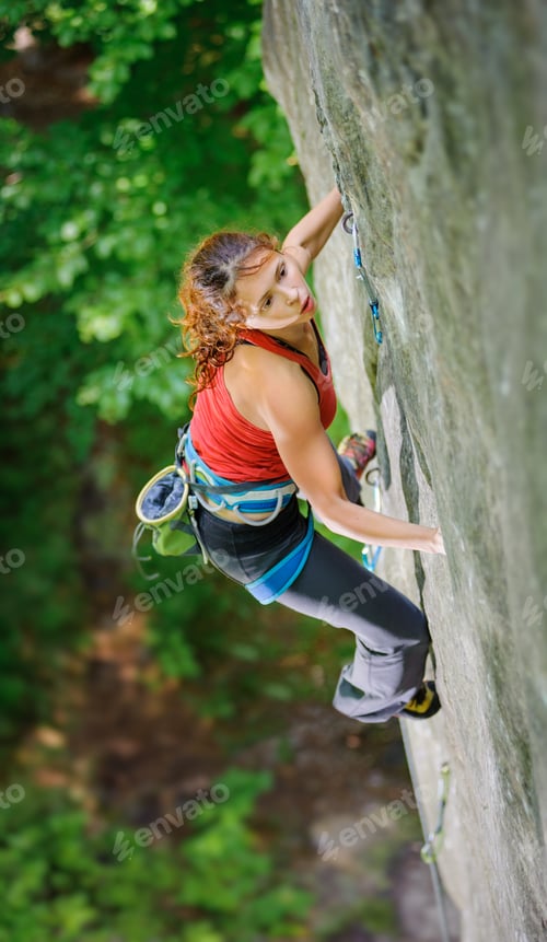 Preview: Beautiful woman climber climbing steep rock with rope