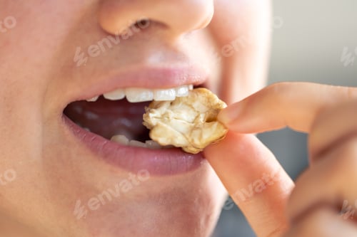 Preview: Detailed shot of a woman bites walnut.