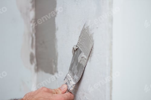 Preview: man hand with trowel plastering a wall, skim coating plaster walls.