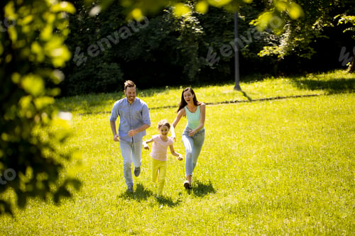 Vista previa: Familia joven feliz con linda hija corriendo en el parque en un día soleado