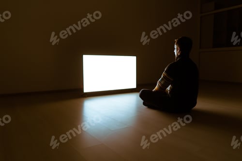 Preview: The man sitting on the floor in front of the television in the dark room