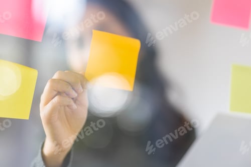Preview: Business female employee with many conflicting priorities arranging sticky notes commenting and