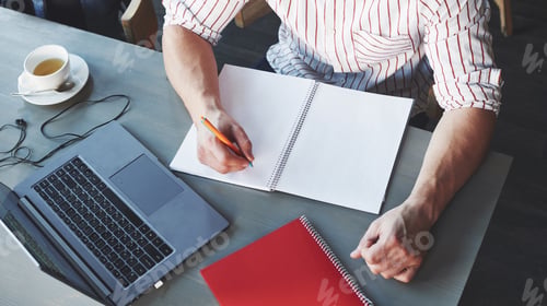 Preview: Top view. Cropped photo of freelance man working on the project with laptop and notepads on table
