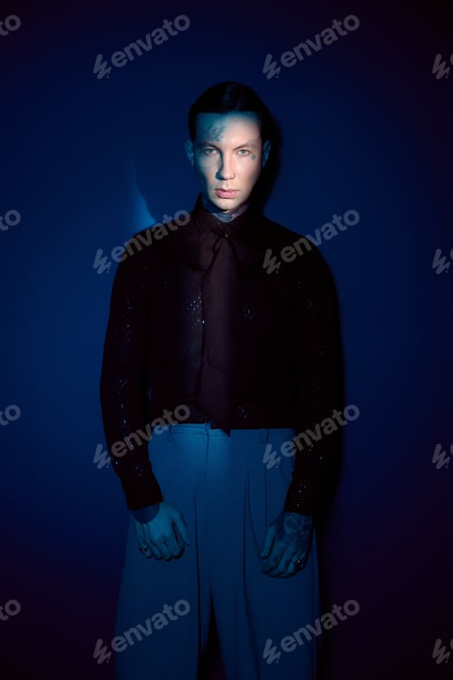 Preview: Young man captures attention with stylish fashion and striking presence in moody lighting