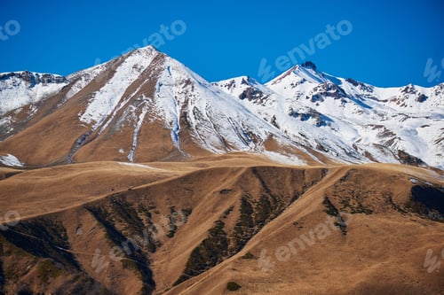 Preview: The stunning contrast of white and brown mountains against the backdrop of a clear blue sky.