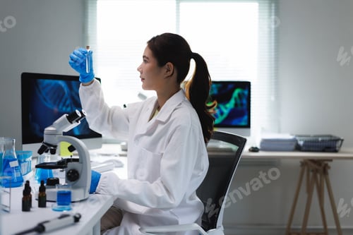 Preview: Woman scientist analyzing liquid in test tube in laboratory