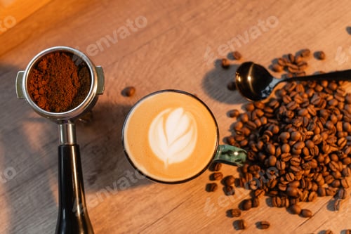 Preview: top view of cappuccino in cup near holder and coffee beans on worktop in coffee shop