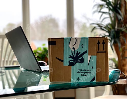 Preview: Delivered Amazon online order box next to laptop on a table