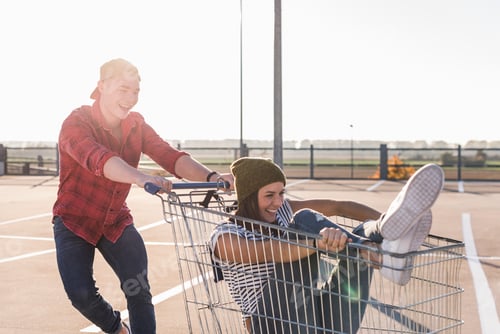 Preview: Playful young couple with shopping cart on parking level