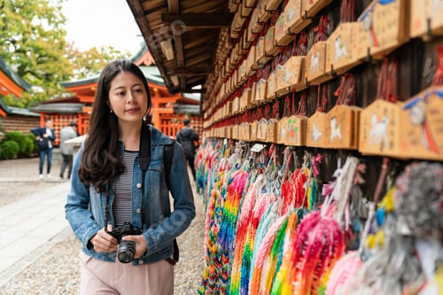 Preview: female walking by a wall of ema and paper cranes