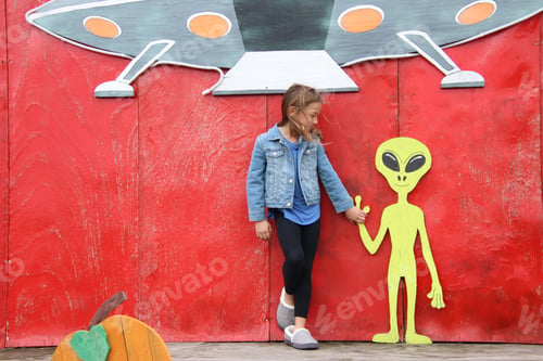 Preview: Girl with red backdrop holding aliens hand spaceship