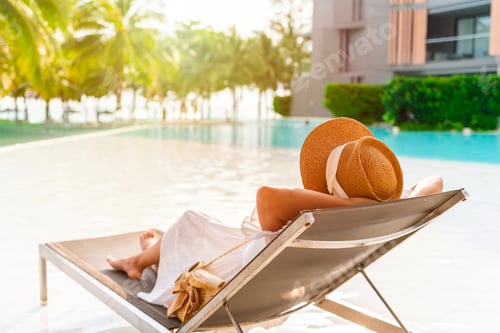 Preview: Young woman traveler relaxing and enjoying the beach view by a tropical resort pool while traveling