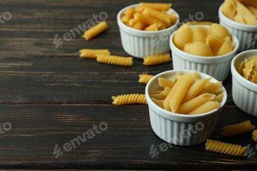Preview: Bowls with uncooked pasta on wooden background