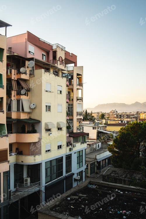 Preview: High angle view of buildings surrounded by greenery with rocks under sunlight on the background