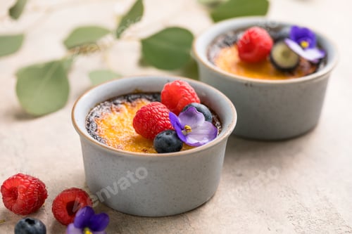 Preview: Creme brulee. French vanilla cream dessert with caramelised sugar and berries, selective focus.