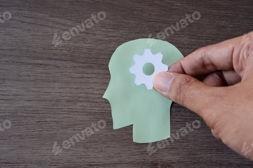 Preview: A green paper cut-out of a human head with a white gear in the center of the head.
