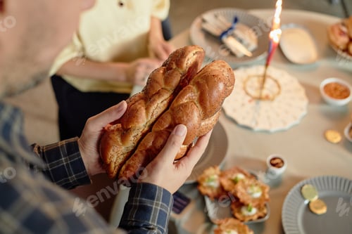 Preview: Caucasian Man Holding Challah Bread during Hanukkah Celebration at Table