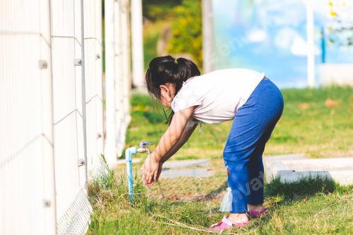 Preview: Child Washing Hands Outdoors on Grassy Area